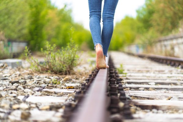 female in jeans walking through the train rails barefoot 1